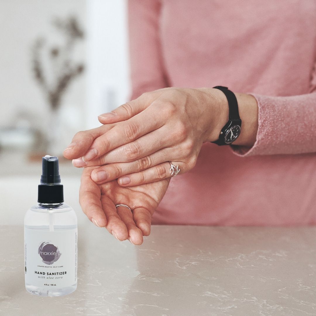 Woman using Moxxie's hand sanitizer spray to clean hands.