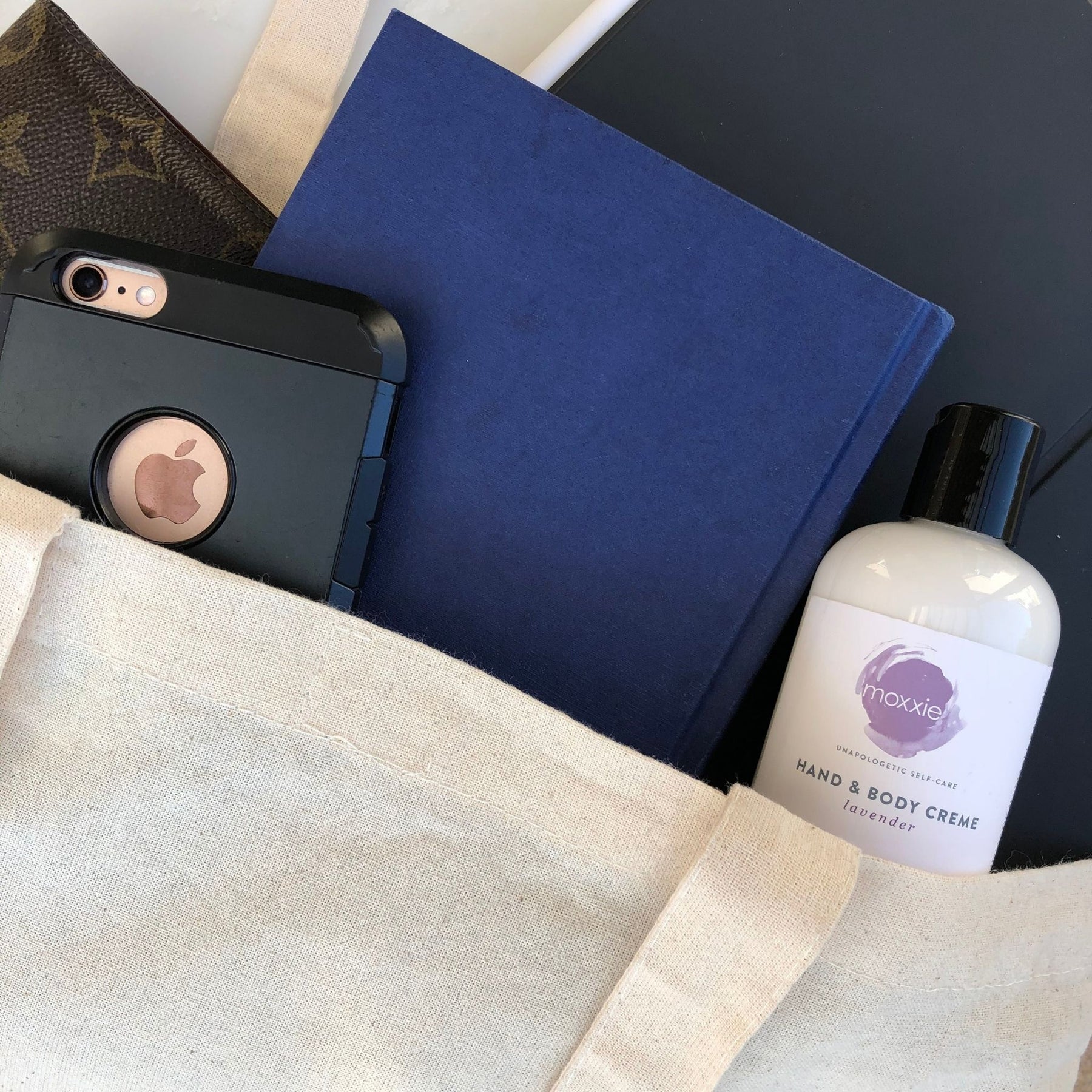 Bottle of Moxxie Essential care rich hand and body creme lotion in a purse